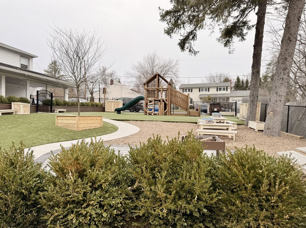 Outdoor playground with artificial turf, woodchip area, and playset with slide