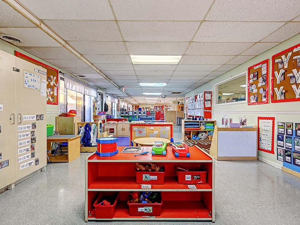 Empty classroom with toys, small furniture, and bulletin boards