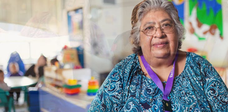 Person wearing glasses and a purple lanyard in a classroom