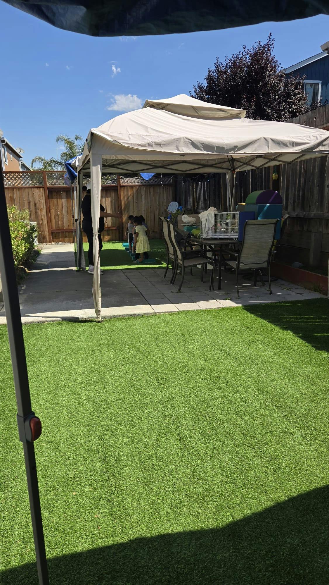 Backyard with artificial grass, a patio, and a canopy over outdoor furniture