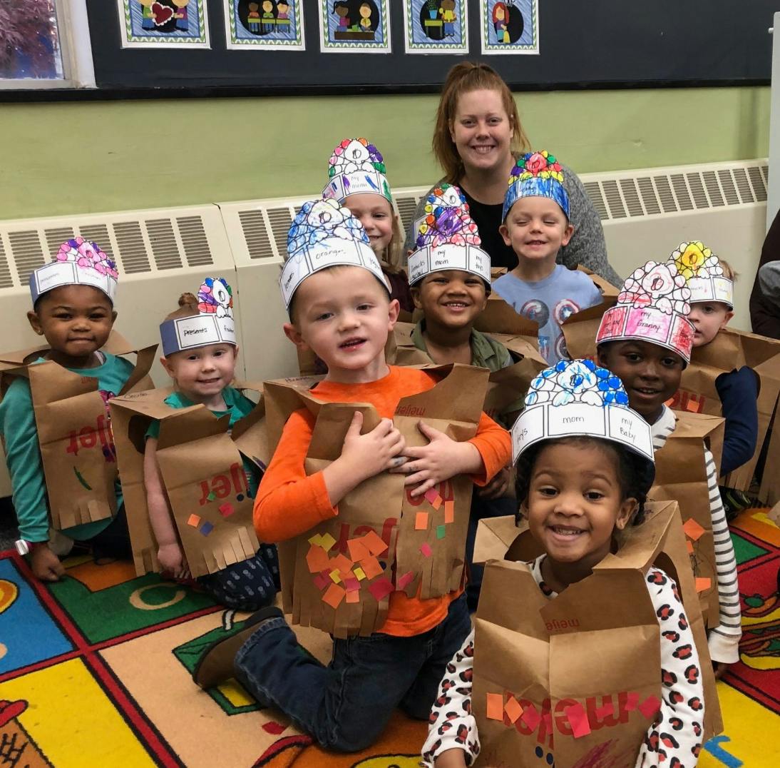 Adult and children wearing paper bag costumes and decorated paper hats