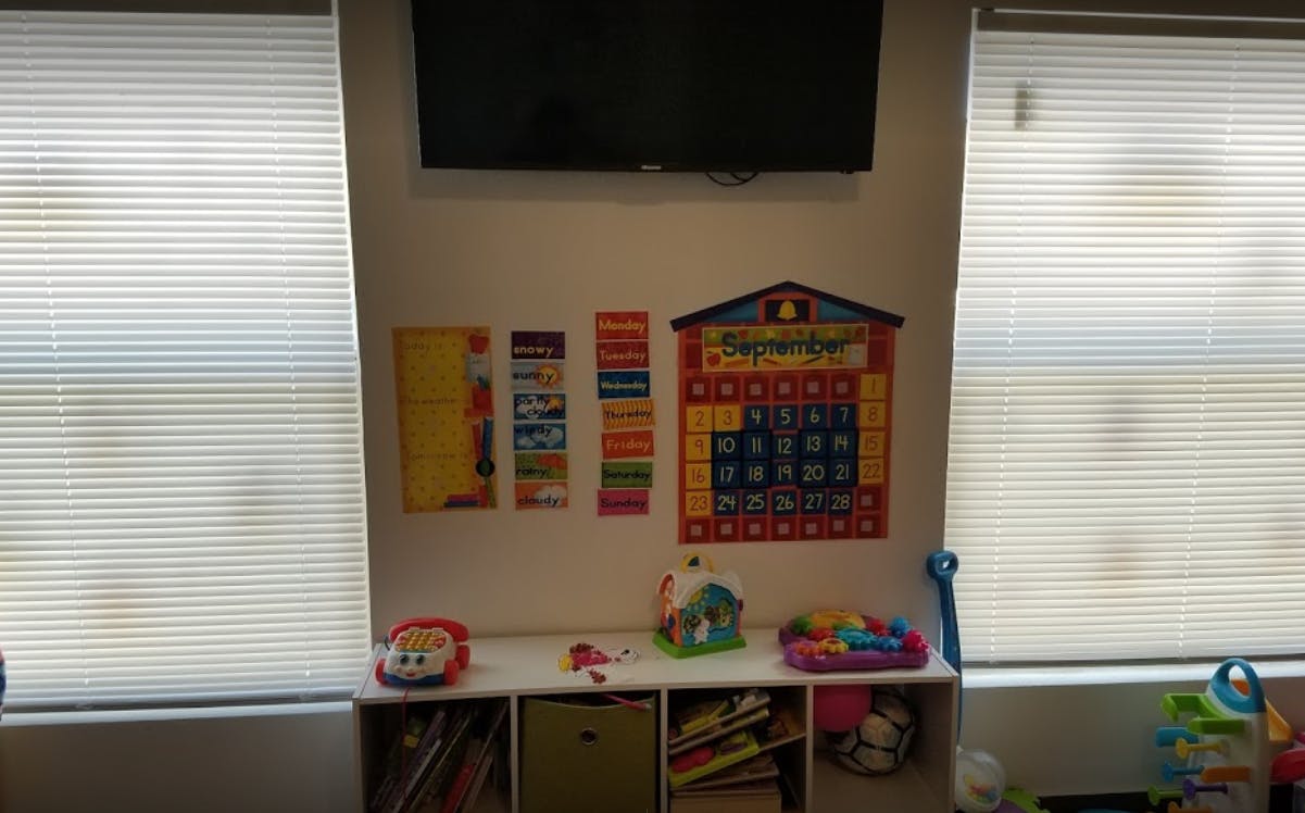 Wall with a calendar, charts, and toys on a shelf below