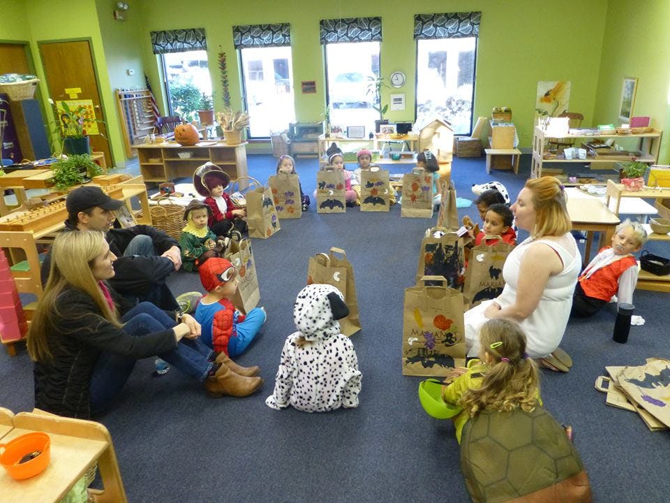 Adults and children sitting on the floor in a classroom