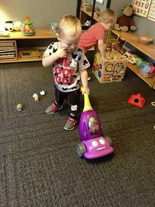 Child playing with a toy vacuum cleaner