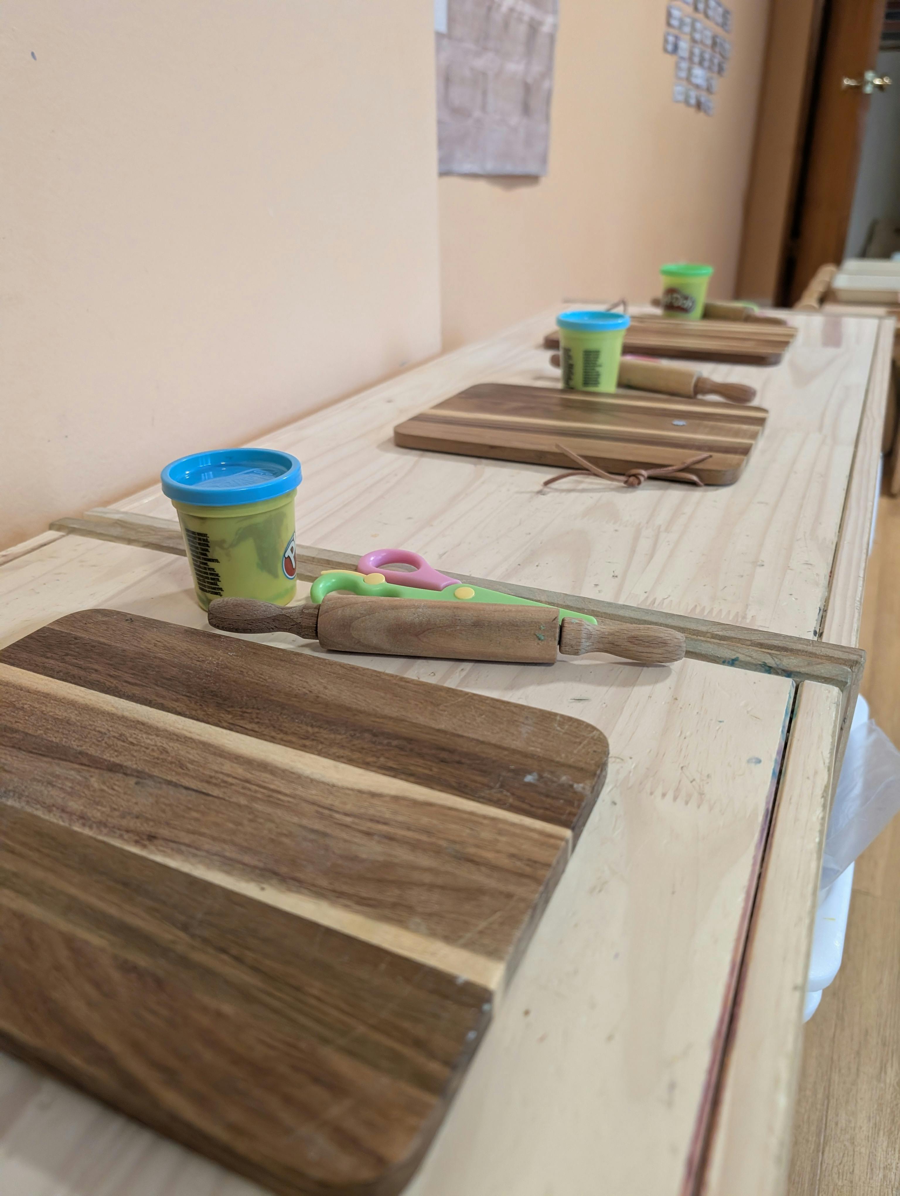 Wooden boards, modeling clay, and rolling pins set on a table for crafts