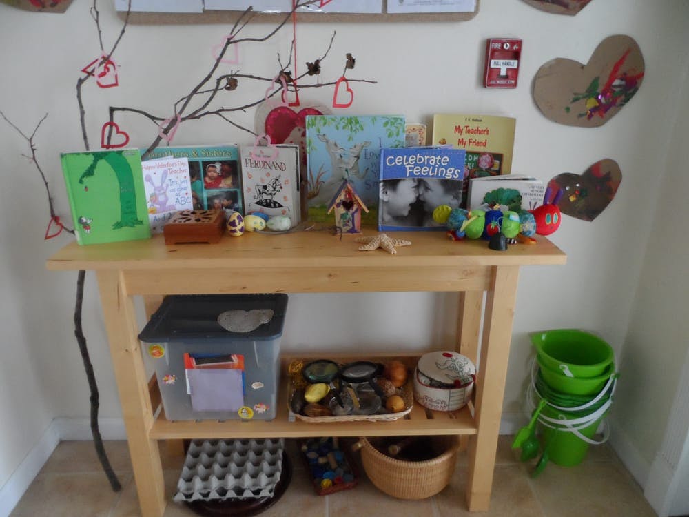 Wooden table with books, toys, and craft supplies