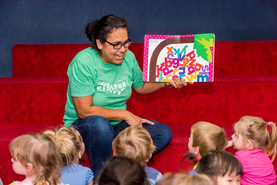 Person reading a book to a group of children