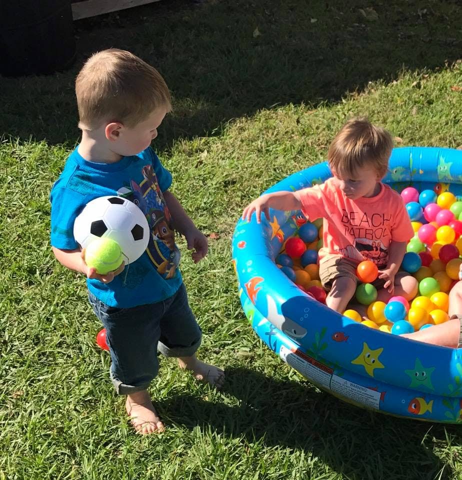 Child holding a soccer ball and a child in a ball pit