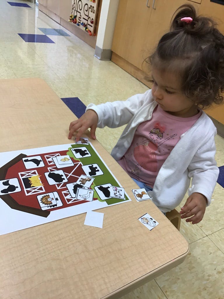 Child playing with a barn-themed matching game on a table