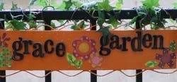 Orange sign with "grace garden" in black letters and floral decorations