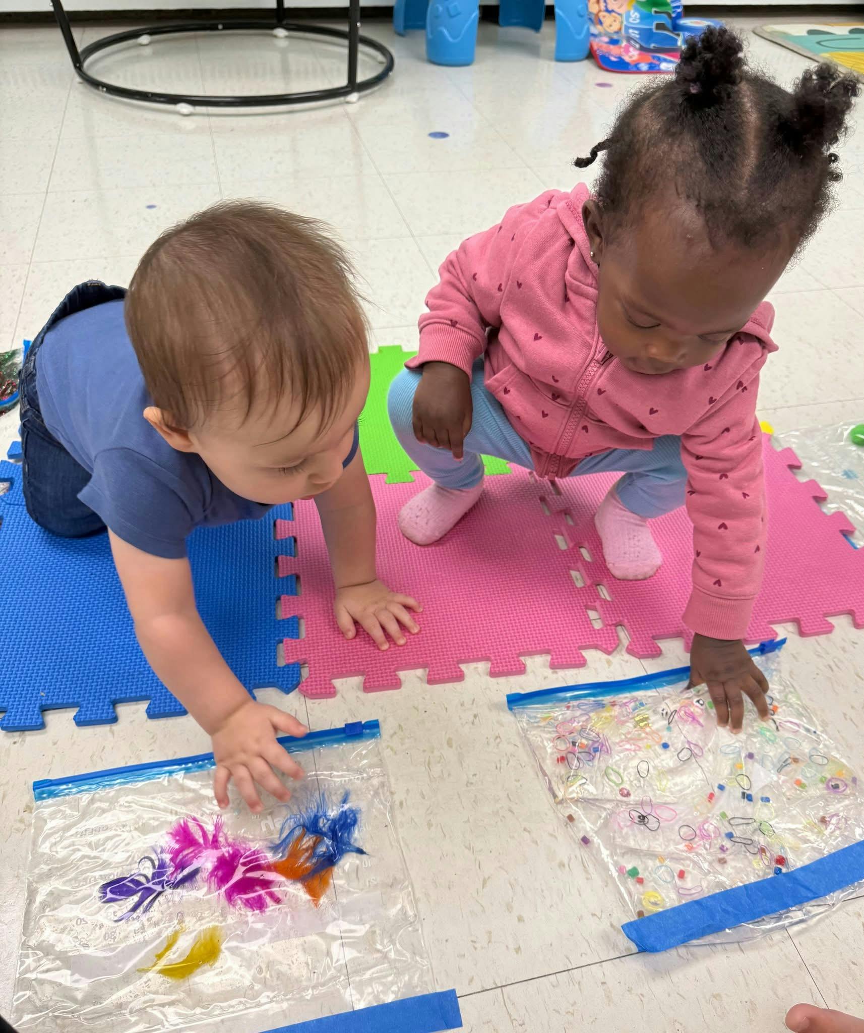 Two children playing with sensory bags on a mat