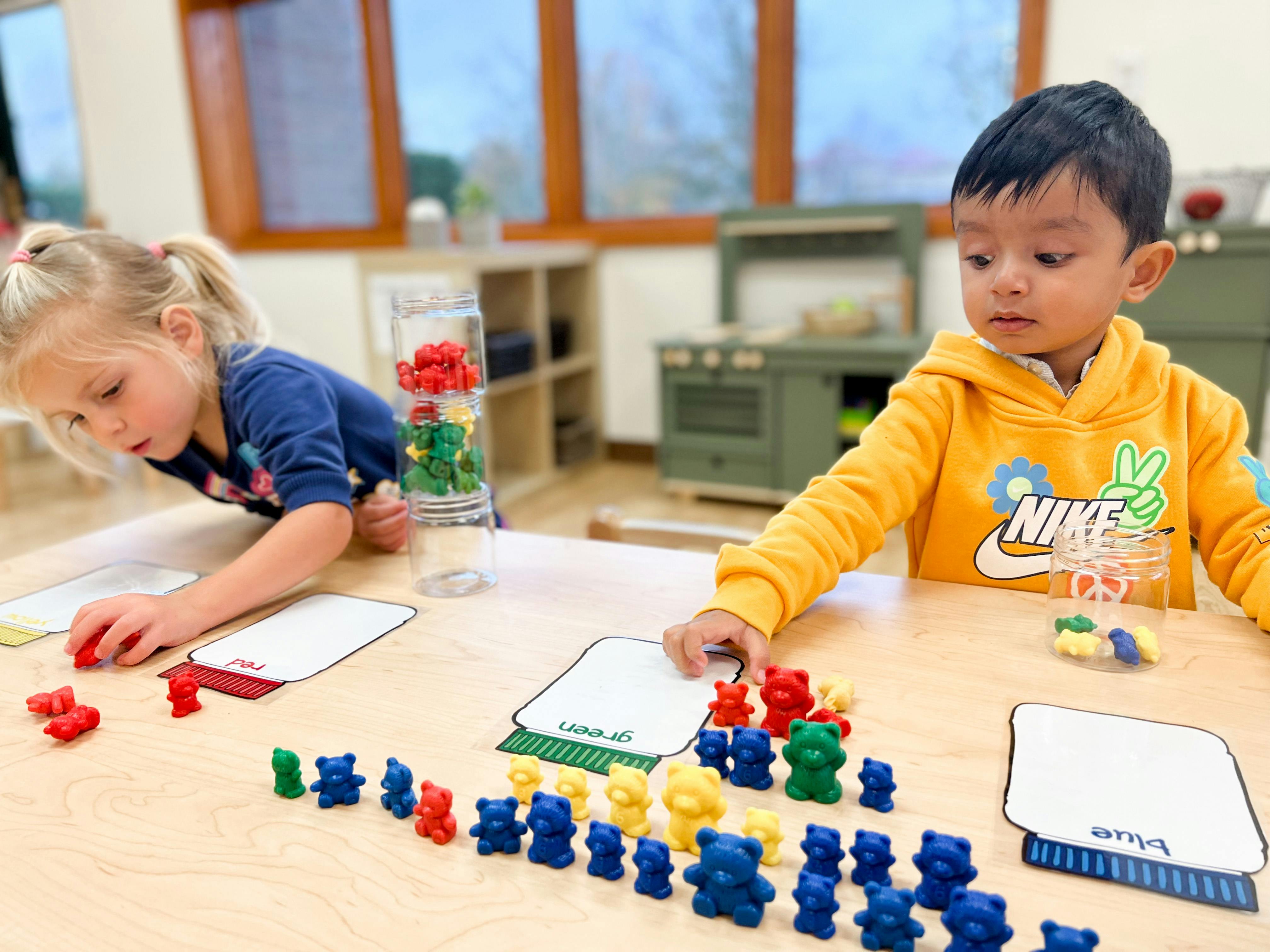 Two children playing with colorful bear counters at a table