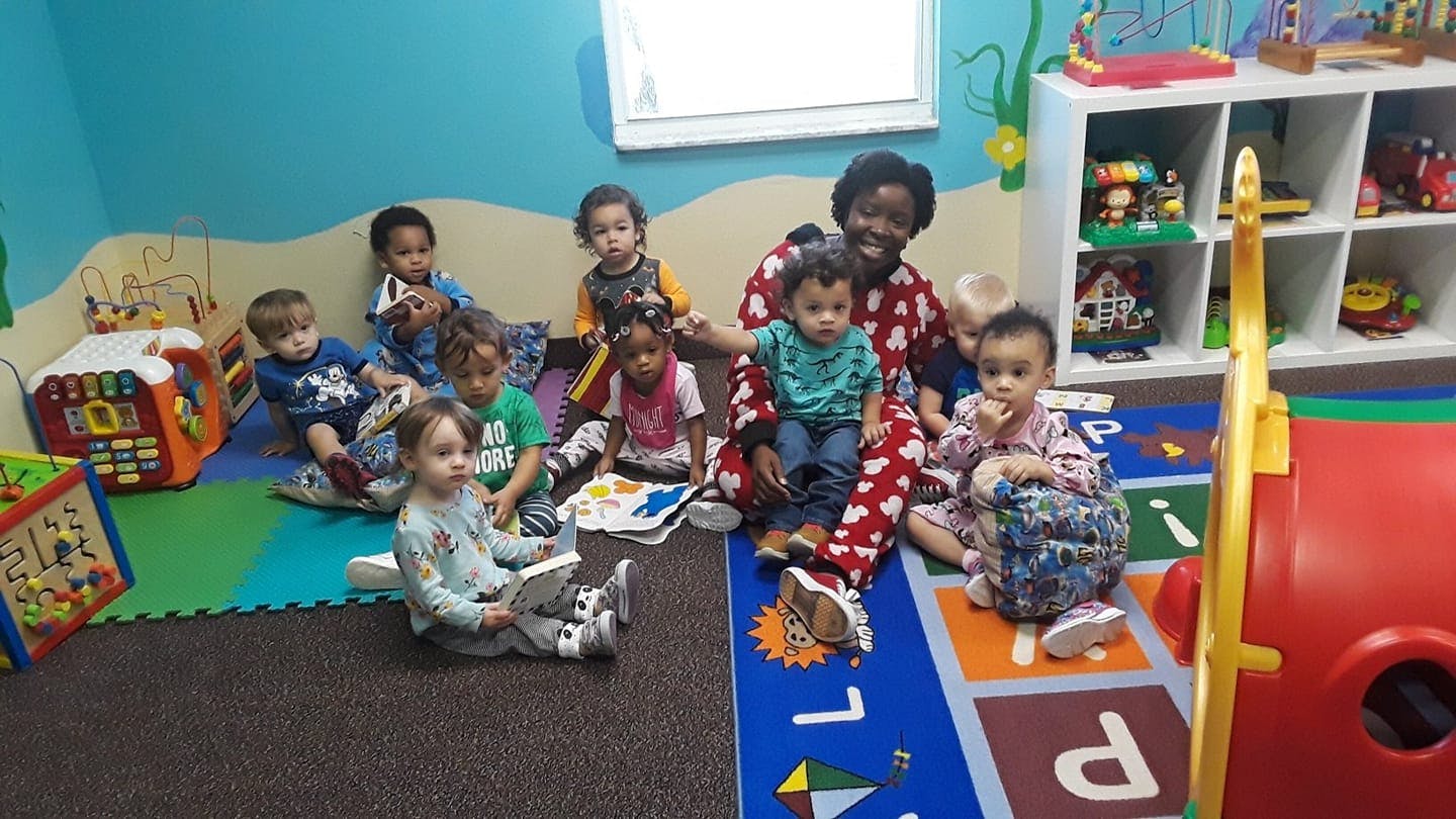 Adult and multiple children sitting on floor in a room