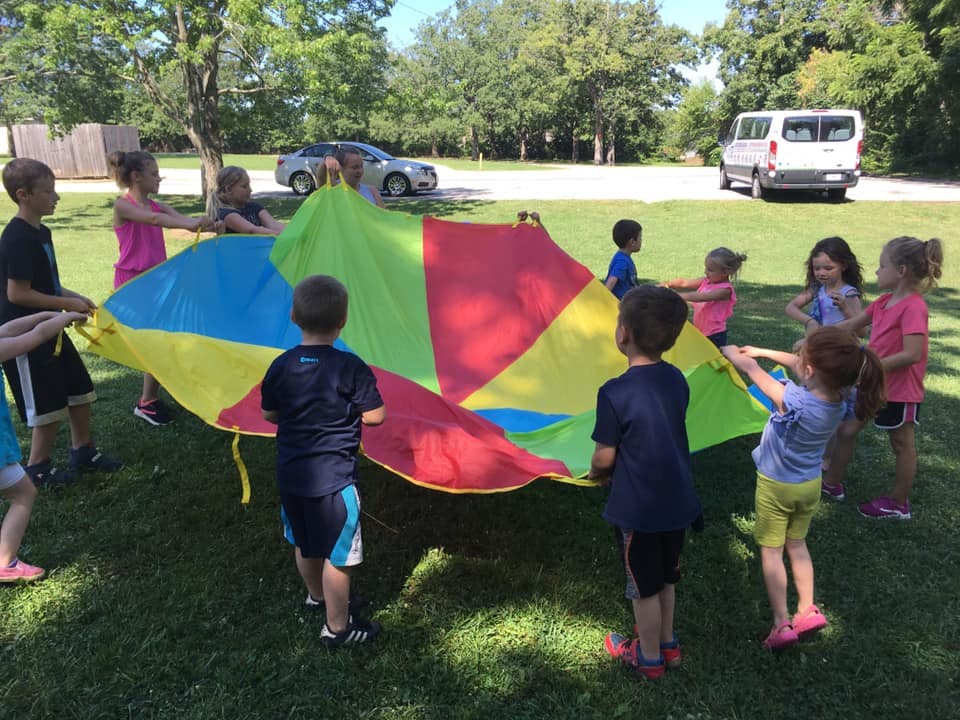 Children playing with a colorful parachute outdoors