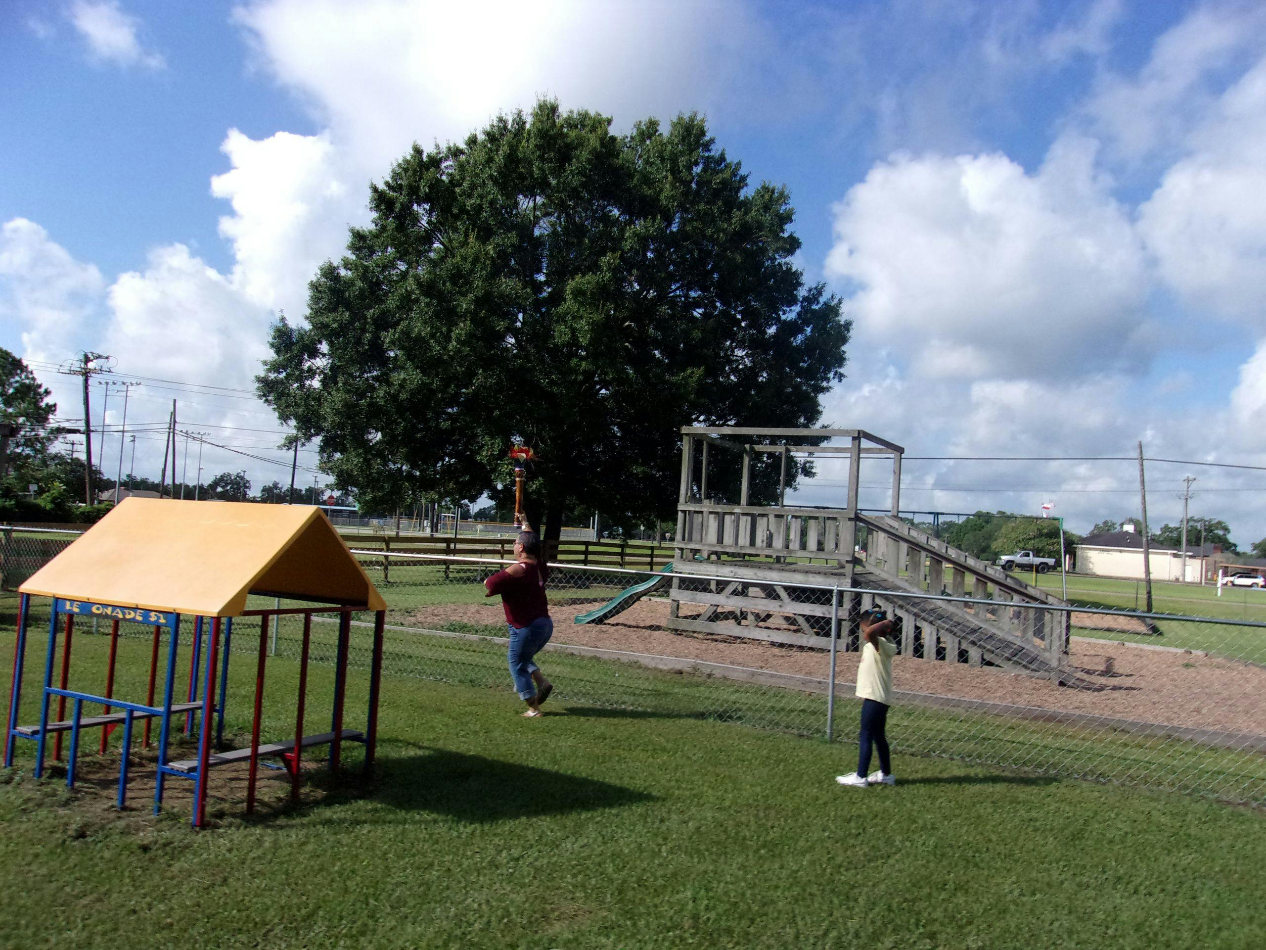 Person on a zip line with another person standing nearby on a playground