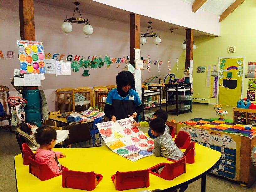 Adult and children looking at a colorful chart in a classroom