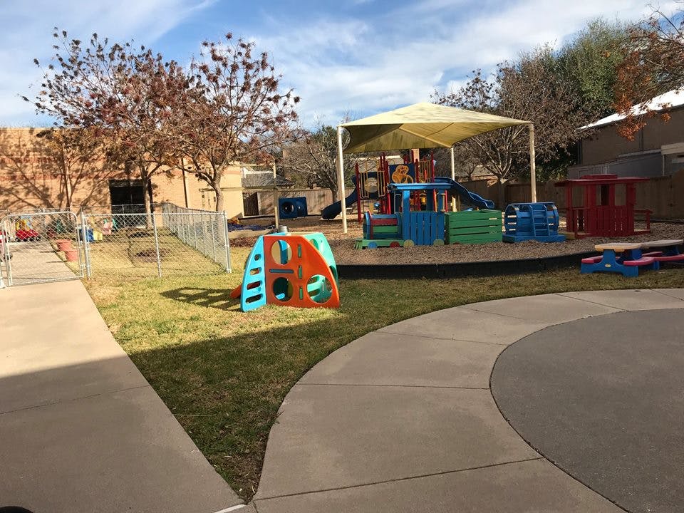 Outdoor playground with various colorful play structures and a shade canopy