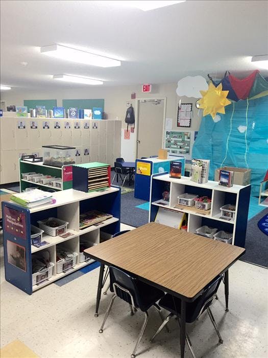 Classroom with small tables and chairs, shelves, and lockers
