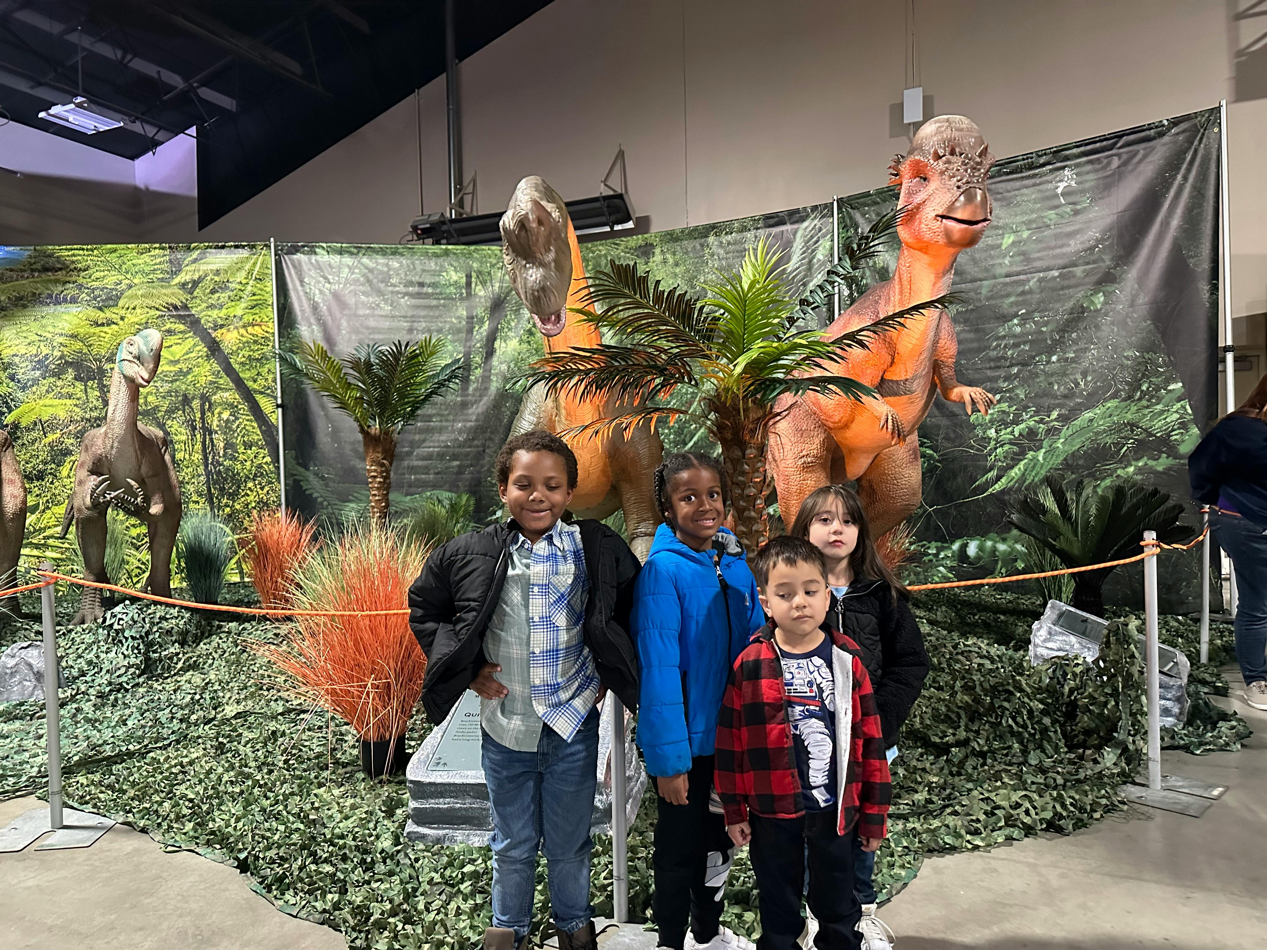 Children posing in front of dinosaur models