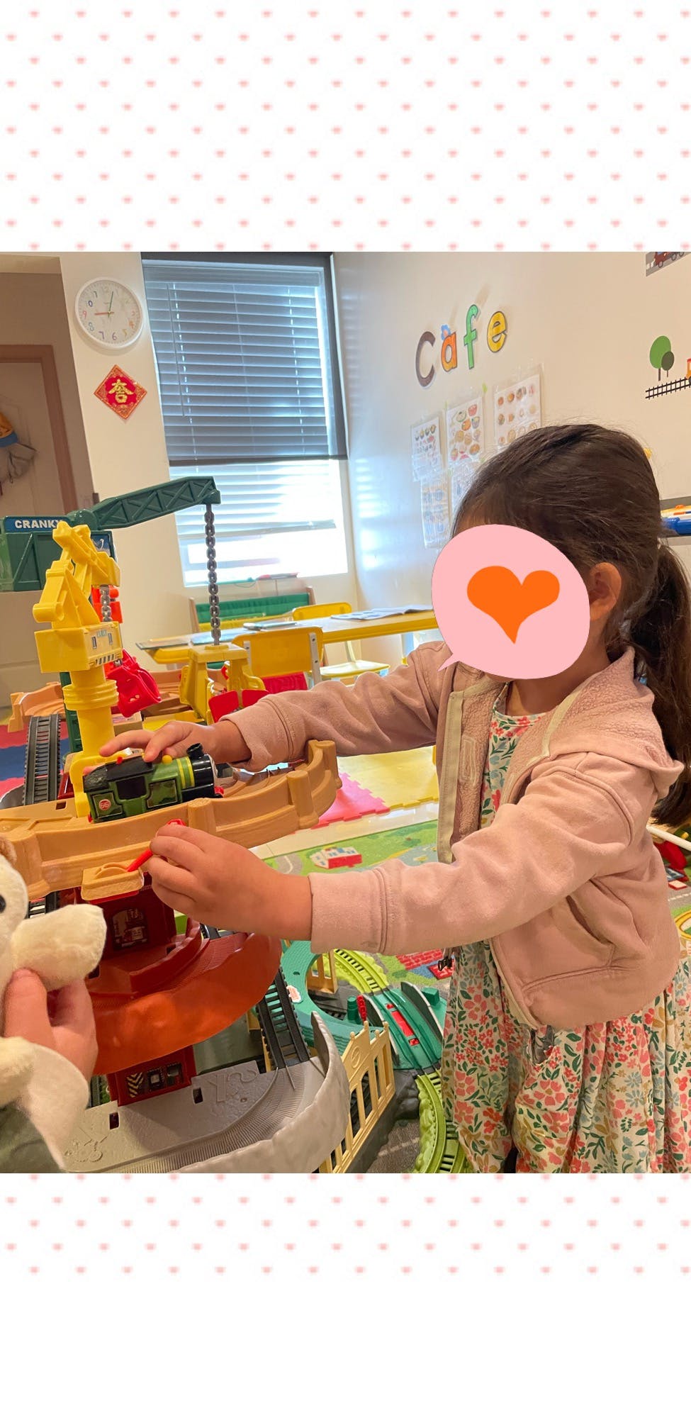 Child playing with a toy train set in a classroom