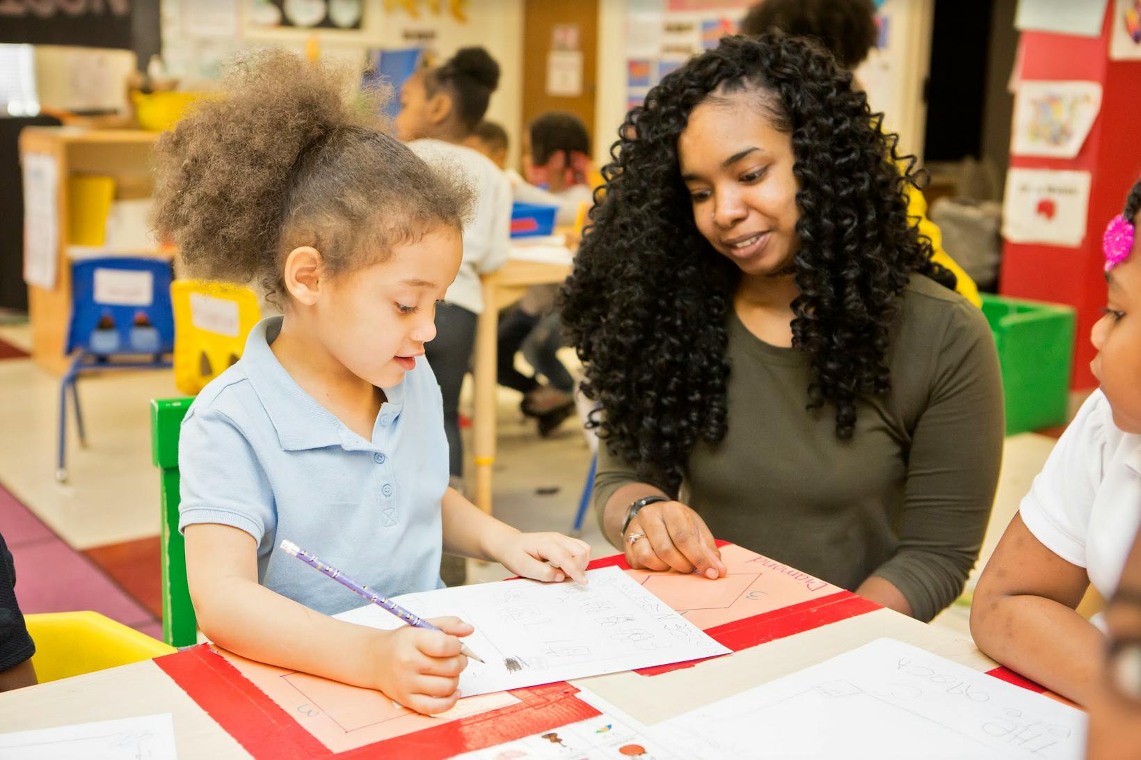 Adult and child looking at papers on a table in a classroom