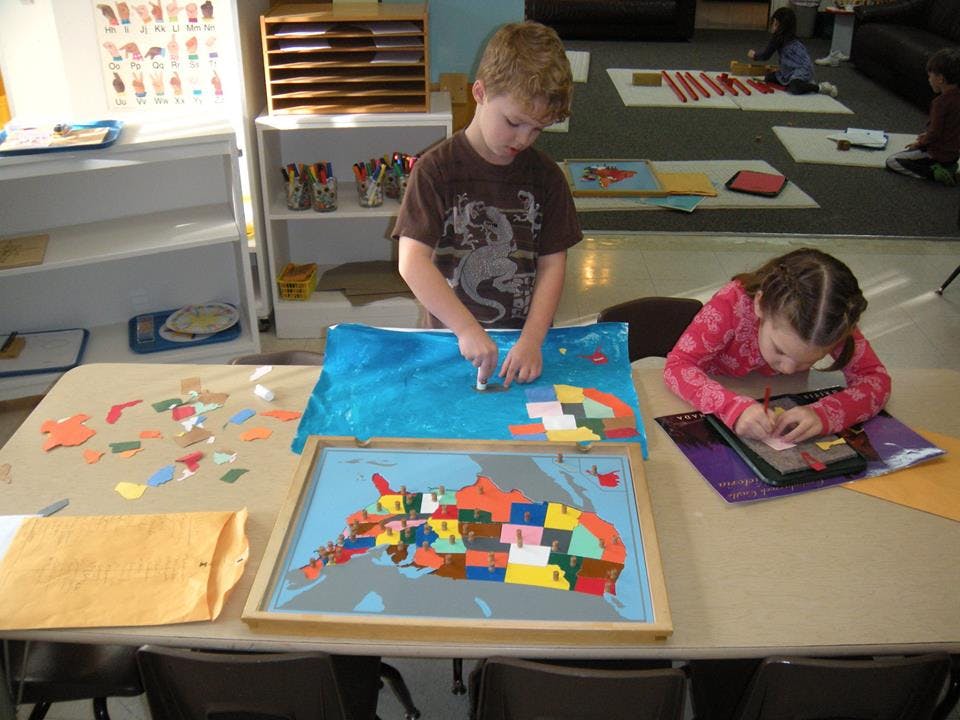 Two children working on puzzles at a table