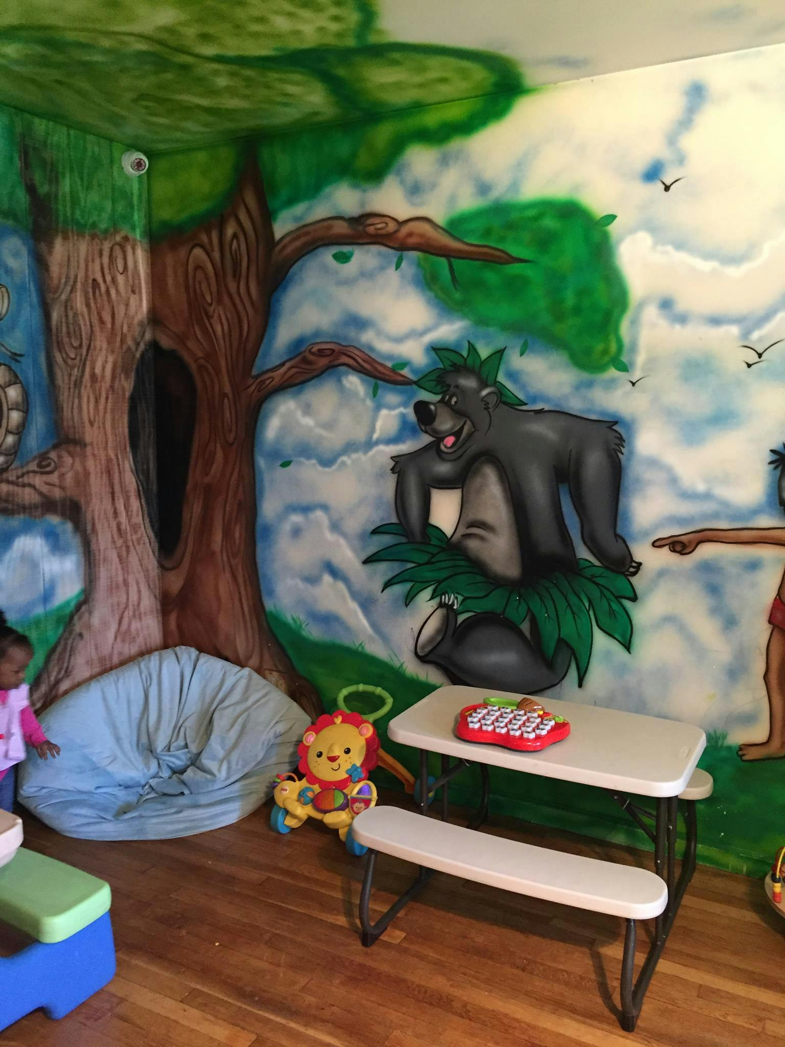 Jungle-themed mural with cartoon characters, a beanbag, and a child's table