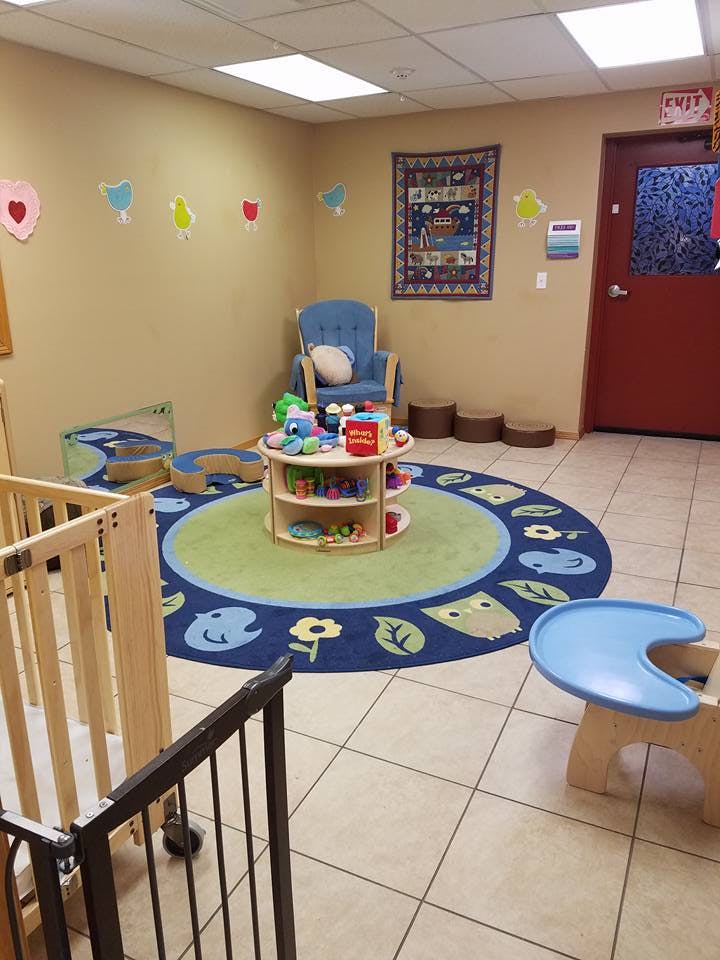 Playroom with a round rug, small table with toys, and a crib