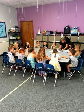 Adult and children sitting around a table in a classroom