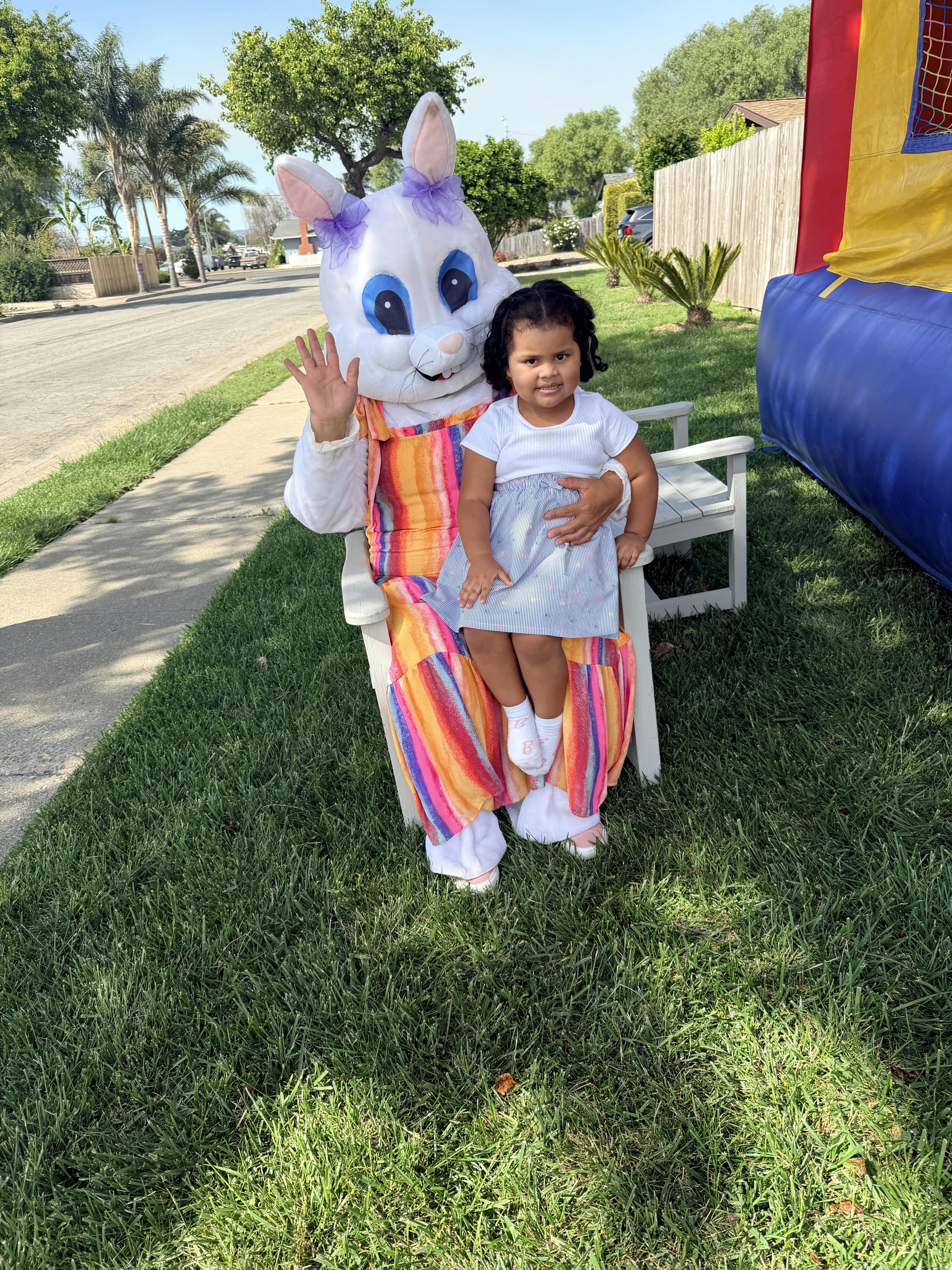 Child sitting on a person in an Easter bunny costume waving
