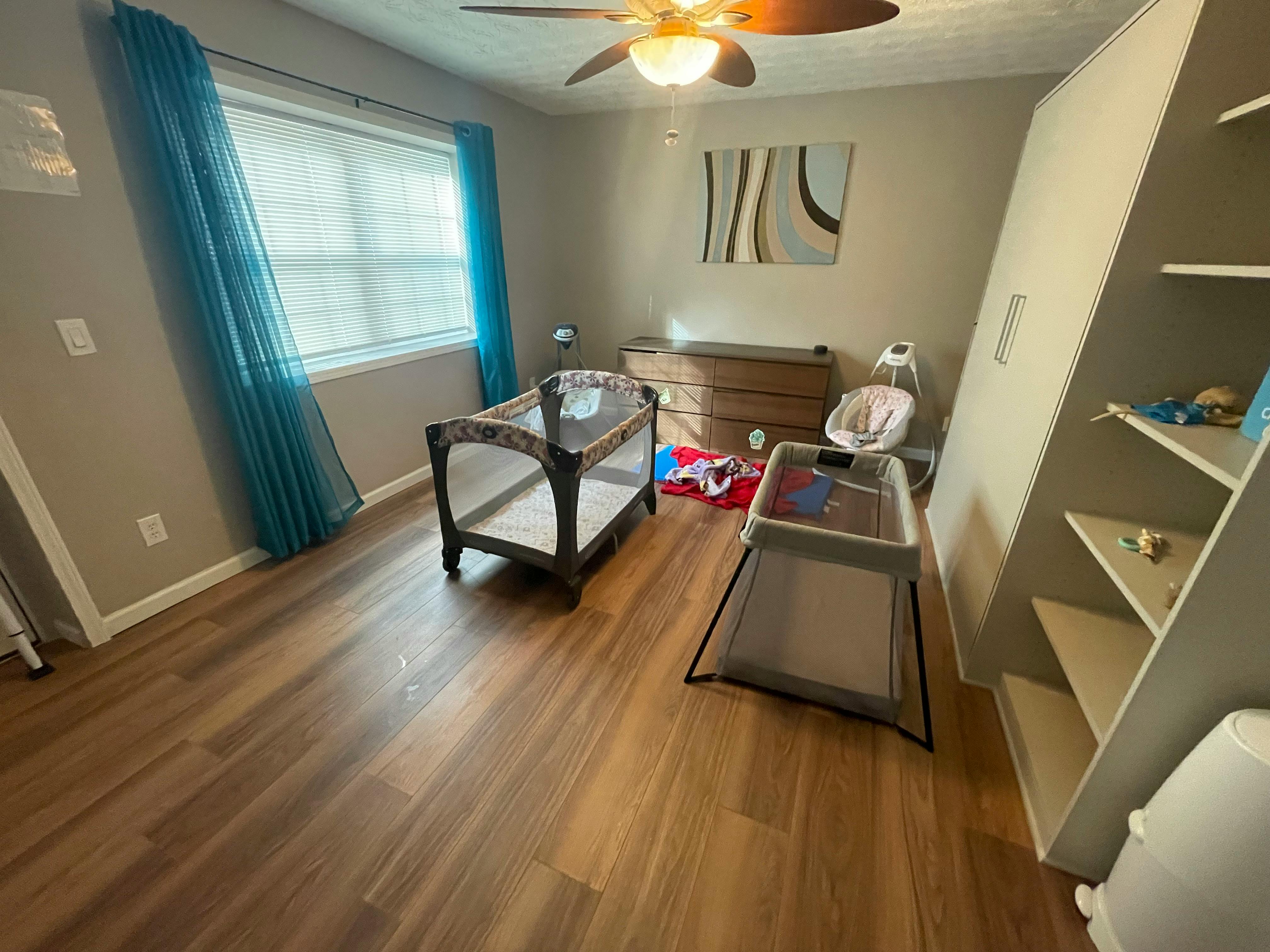 Nursery room with a changing table, playpen, and baby bouncer