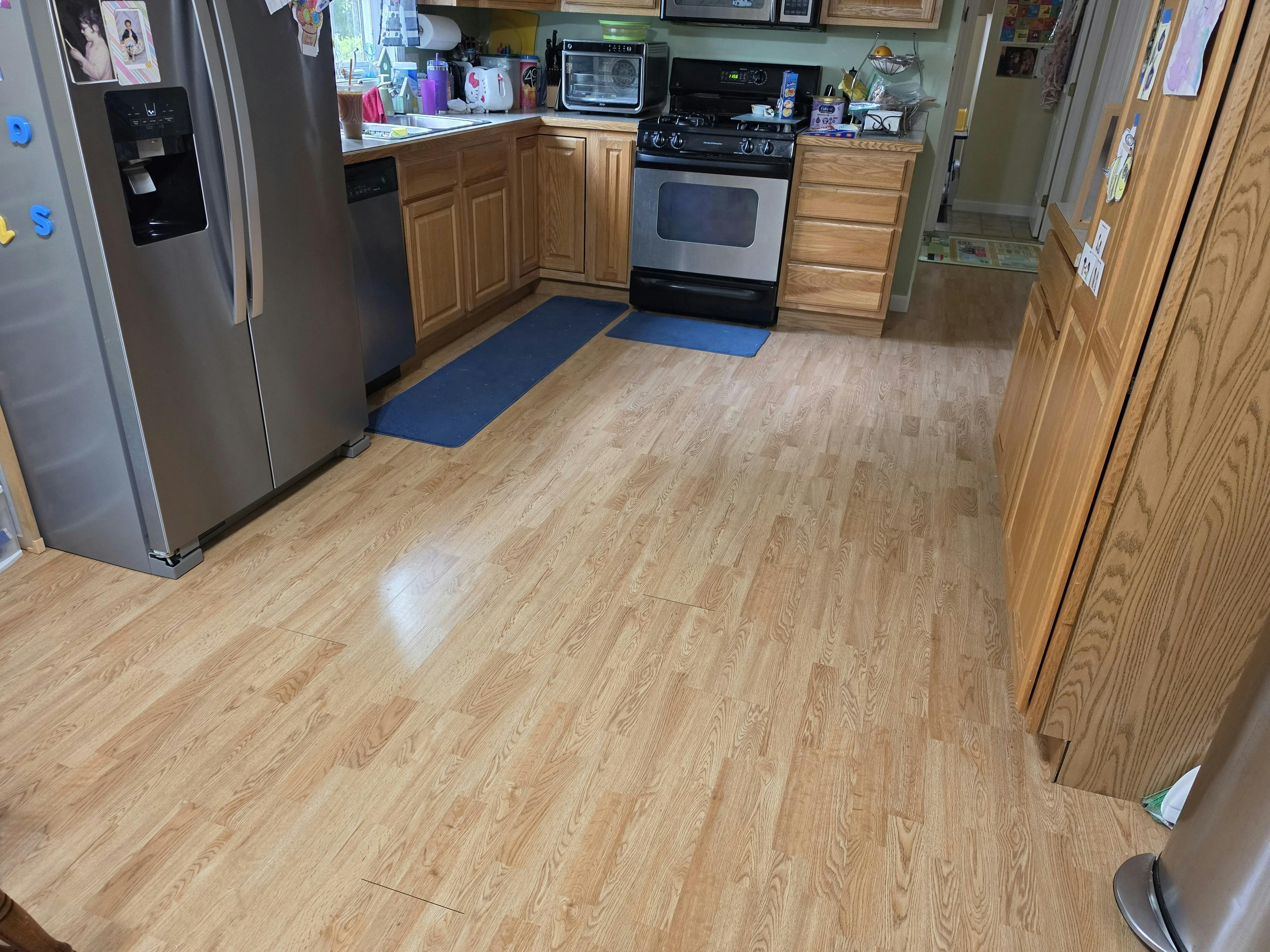 A kitchen with light wood-style flooring, stainless steel appliances, and wooden cabinets