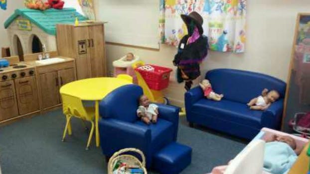 Playroom with toy kitchen, yellow table, blue chairs, and dolls