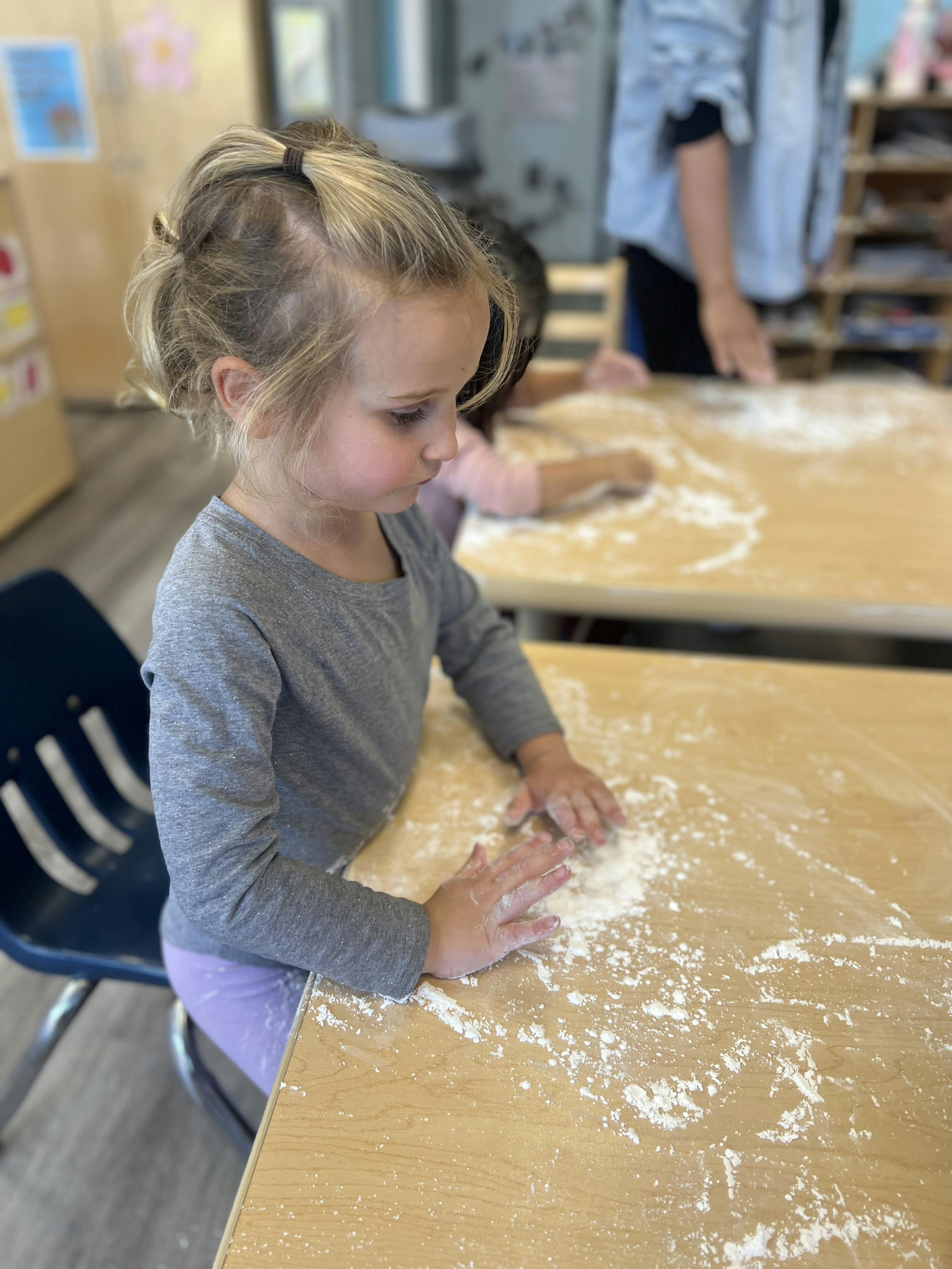 Child playing with flour on a table