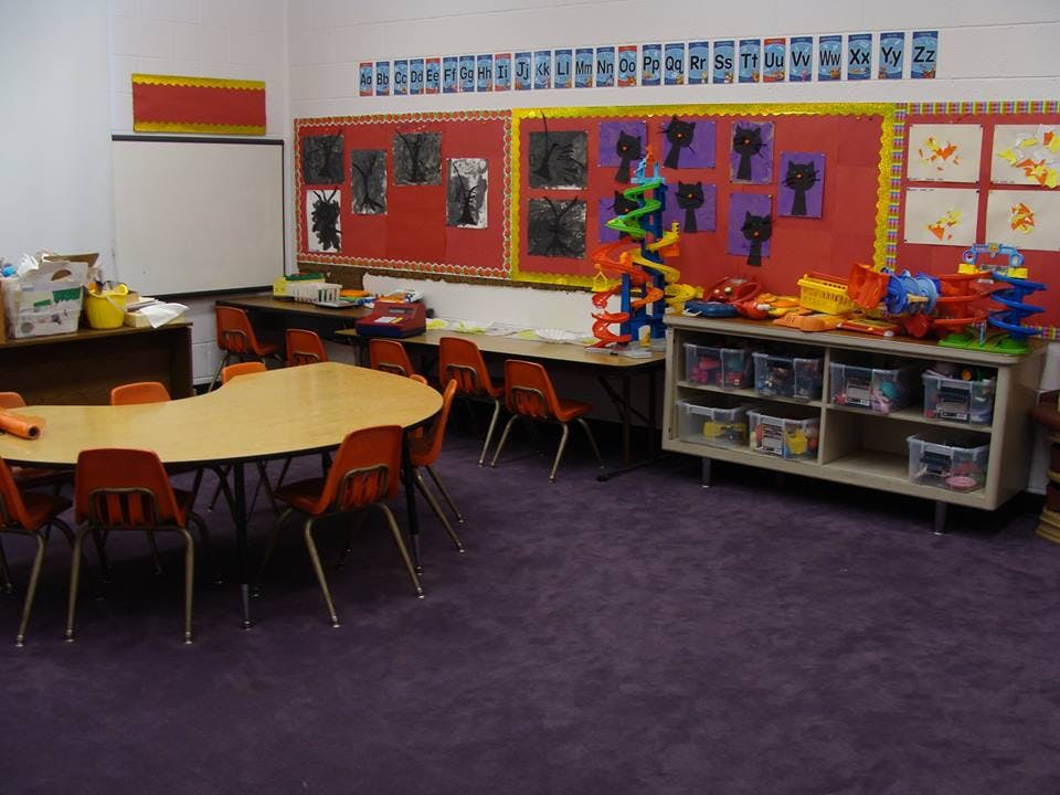 Classroom with small tables and chairs, bulletin boards, and toys