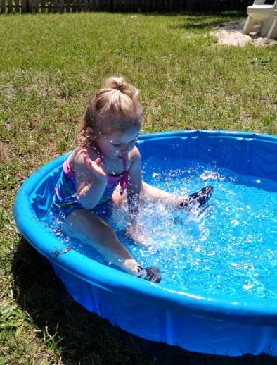 Child splashing in a blue wading pool