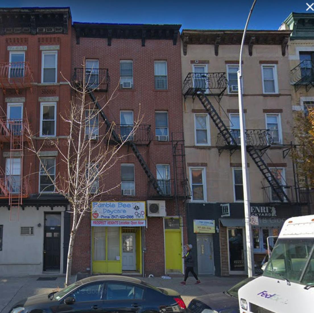 Row of brick buildings with fire escapes and storefronts