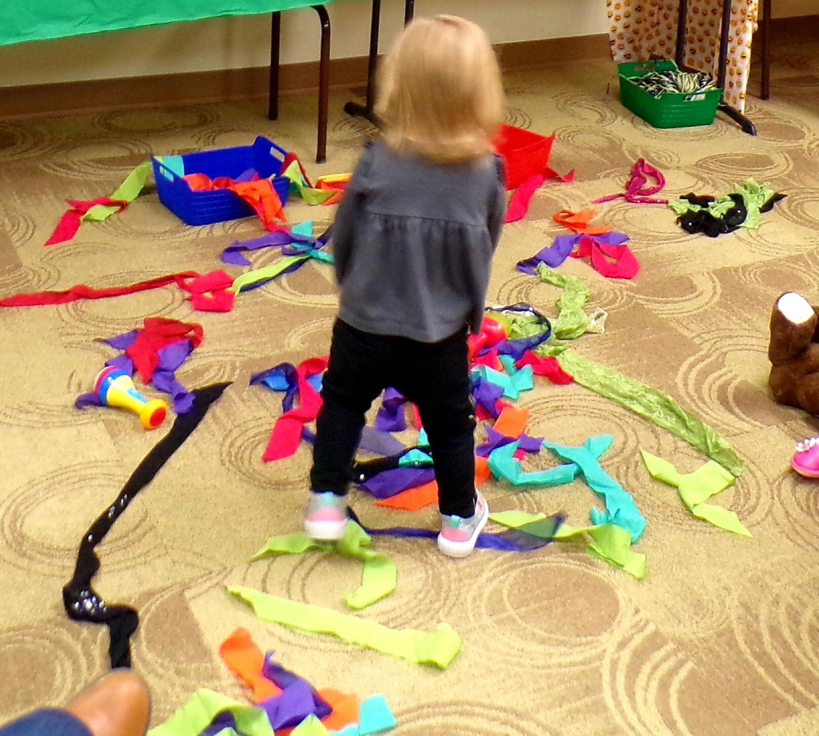 Child standing on a pile of colorful fabric scraps on the floor