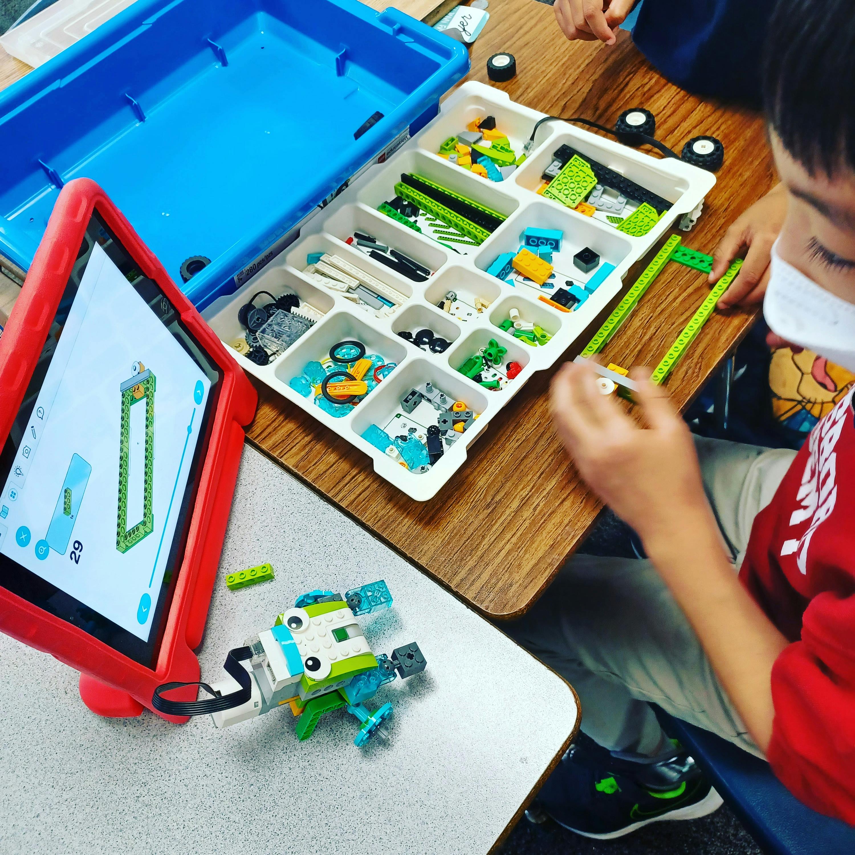 Child building with colorful blocks and looking at a tablet
