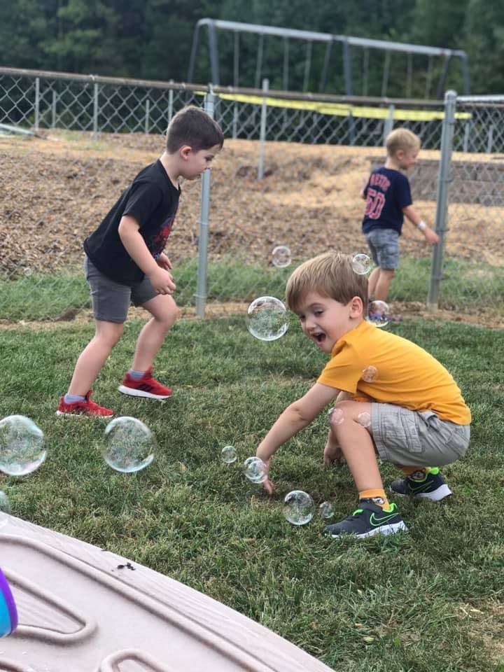 Three children playing with bubbles on grass