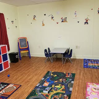 Playroom with small table and chairs, easel, and play mats