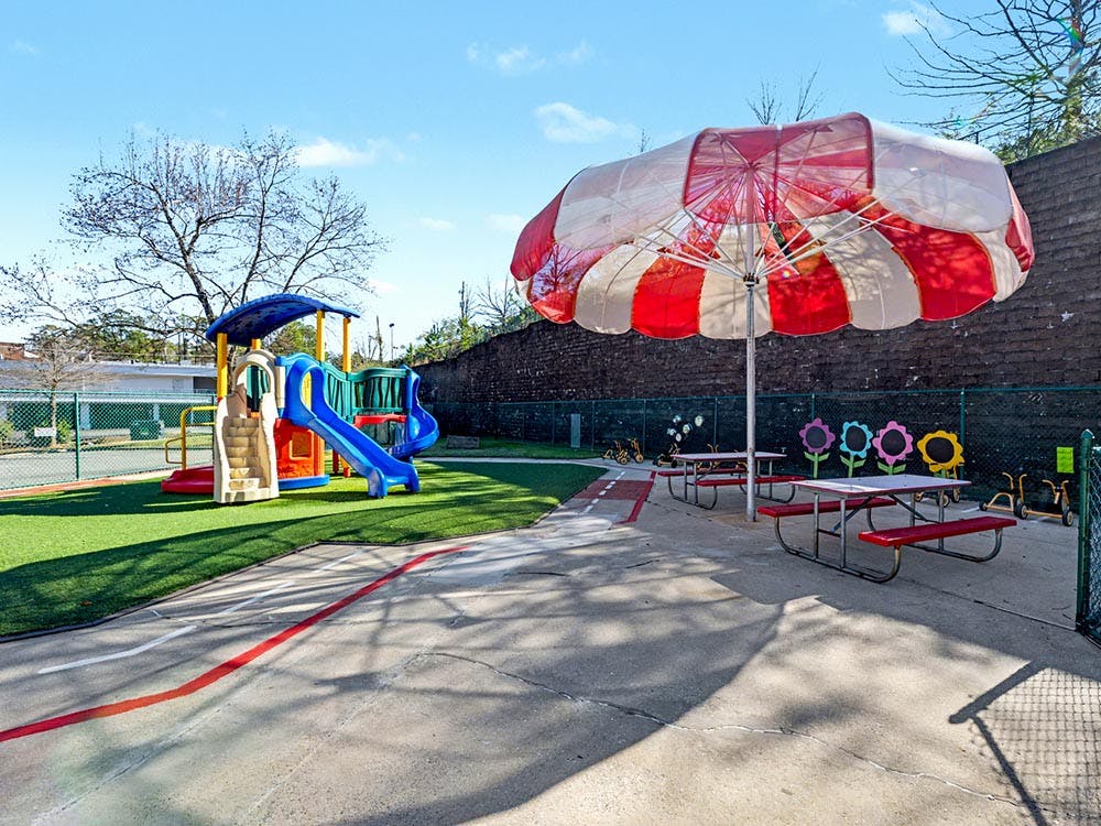 Playground with colorful play structure, picnic tables, and a large umbrella