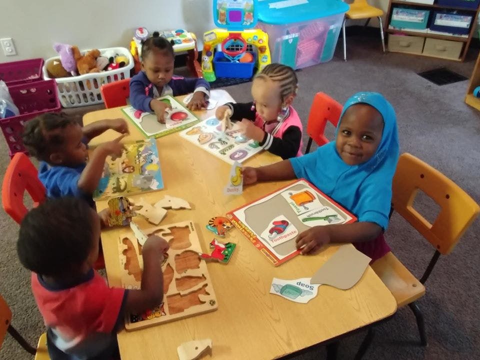 Four children sitting at a table with learning activities