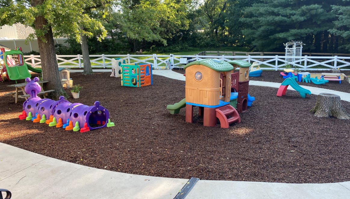 Outdoor playground with various play structures and wood chip ground cover