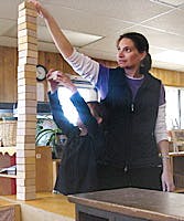 Person reaching up to a tall stack of blocks