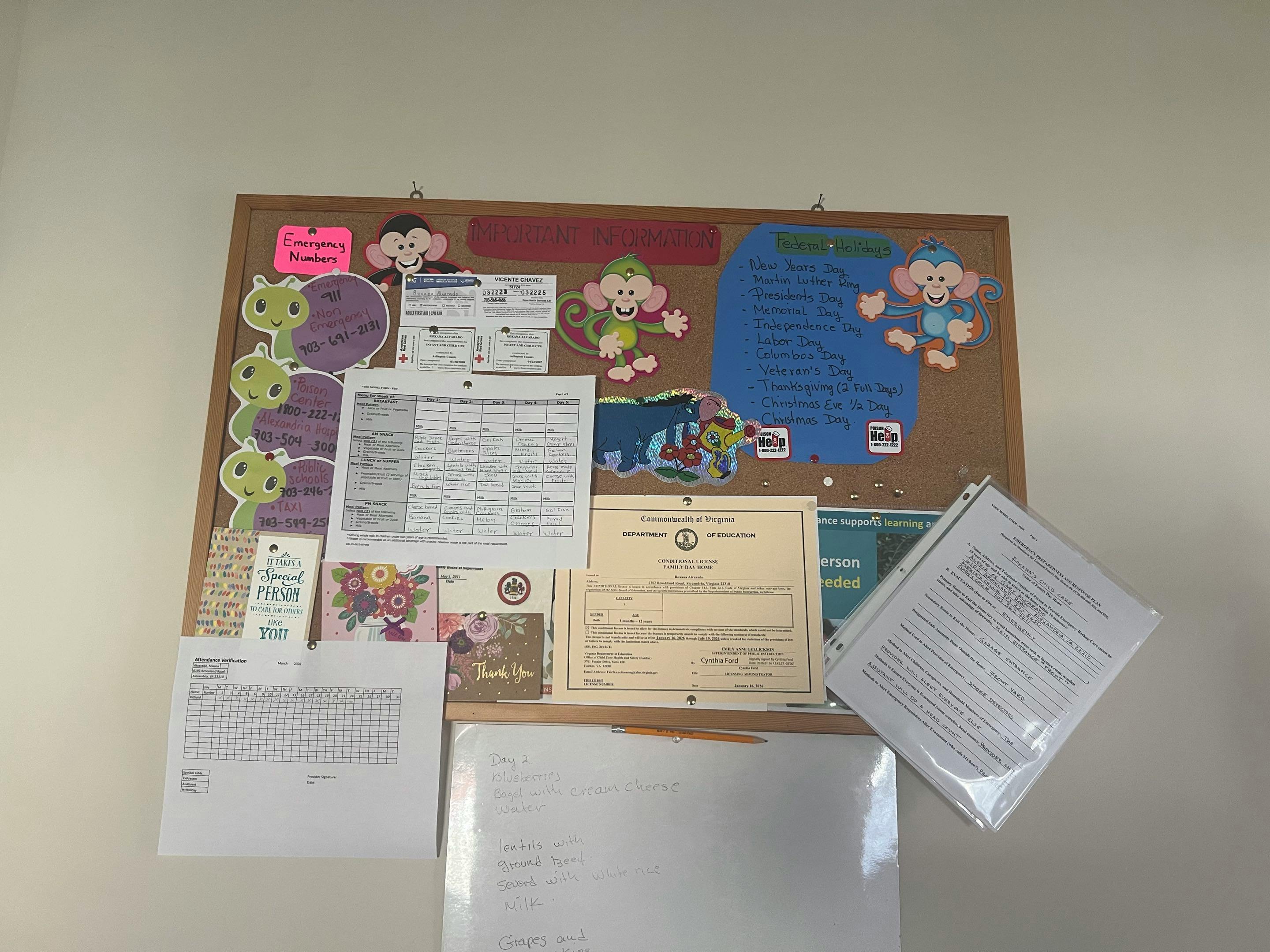 Bulletin board with papers and cutouts, including emergency numbers and federal holidays