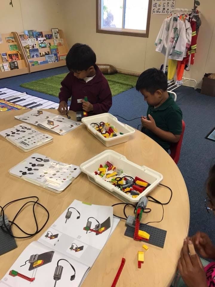 Two children building with colorful blocks and following instructions at a table
