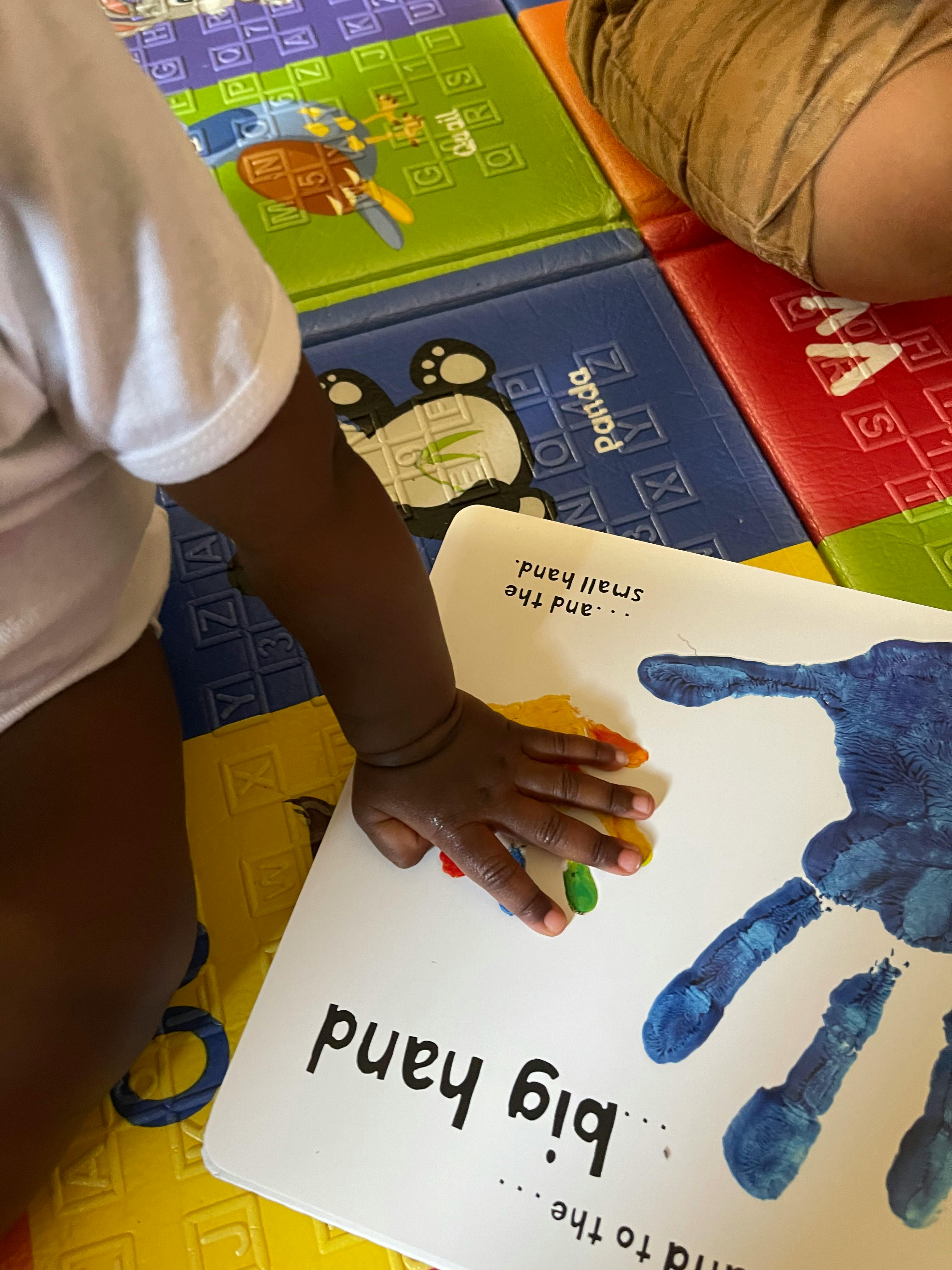 Child's hand on a book with text "big hand" and a blue handprint