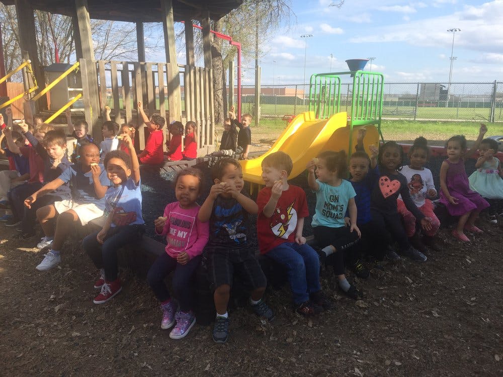 Group of children sitting on the ground near a playground slide