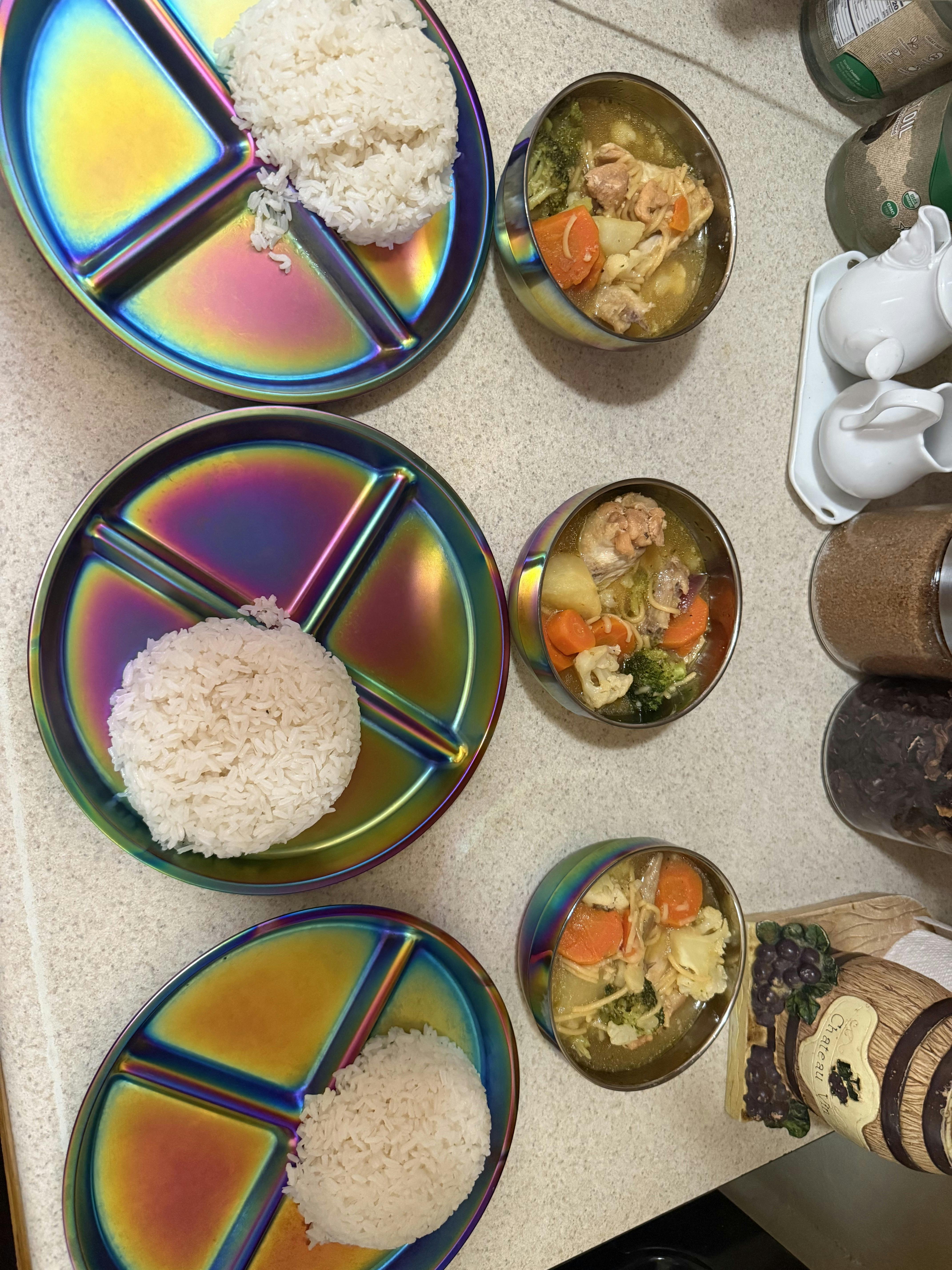 Three plates of white rice paired with three bowls of vegetable chicken soup